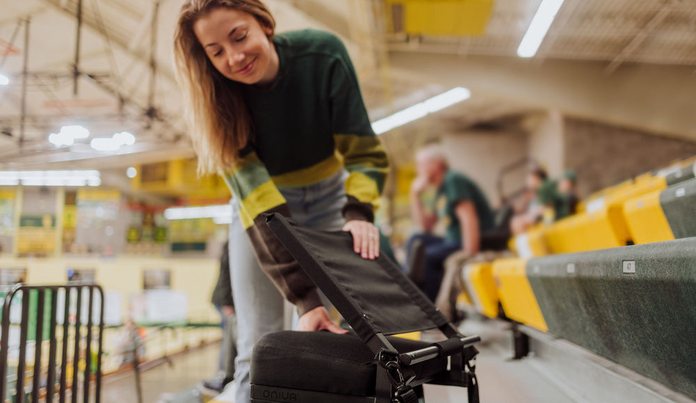 woman setting collapsible stadium seat on the bleachers during a basketball game