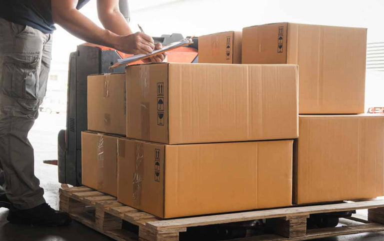 Writing paperwork on top of a pallet of boxes