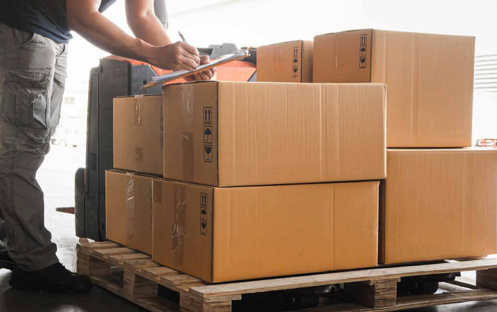 Writing paperwork on top of a pallet of boxes